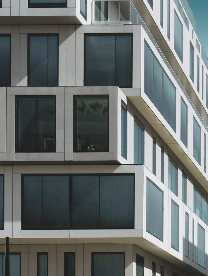 grey-concrete-building-with-big-windows-blue-sky_181624-5695